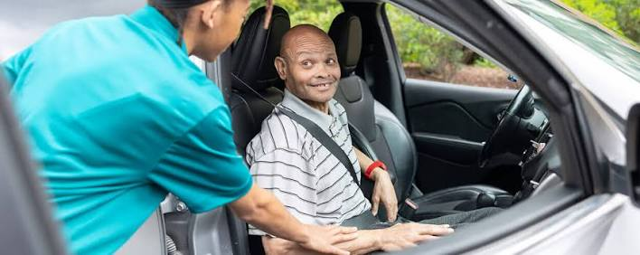 A compassionate driver assisting a passenger into a vehicle